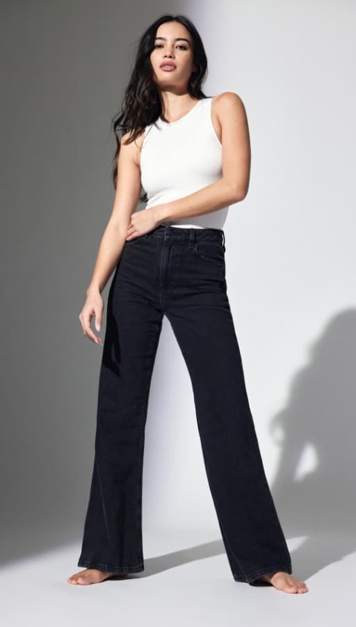 A model wears black wide-leg jeans with a white racer tank.